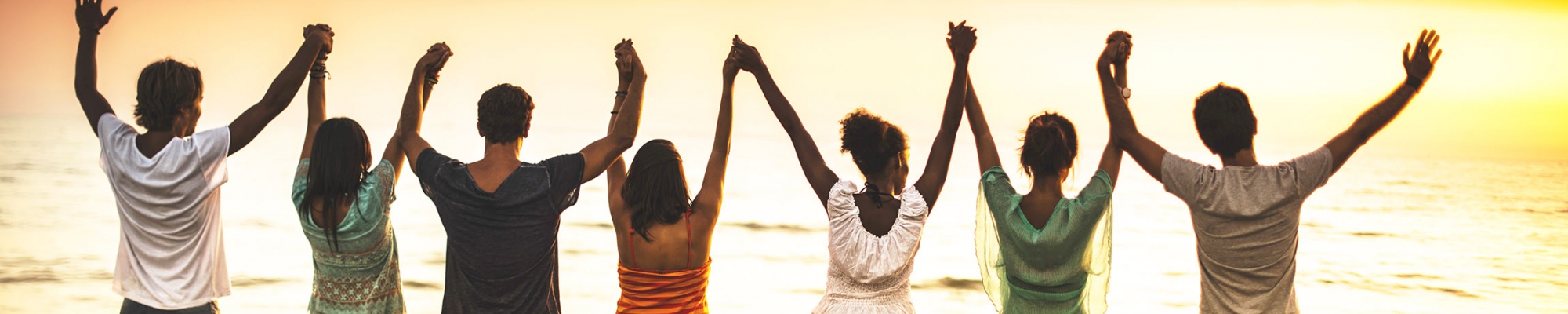 People standing on beach with hands raised